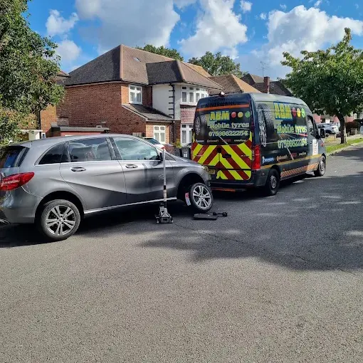ABM Mobile Tyres van providing roadside tyre replacement for a silver Mercedes B-Class on a residential street